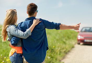 Image showing couple hitchhiking and stopping car on countryside