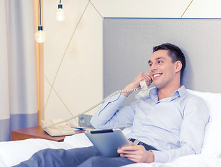 Image showing businessman with tablet pc and phone in hotel room