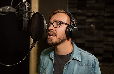 Image showing man with headphones singing at recording studio