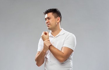 Image showing unhappy man suffering from pain in hand