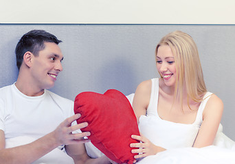 Image showing smiling couple in bed with red heart shape pillow