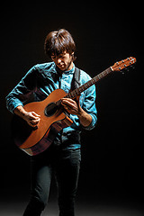 Image showing Cool guy standing with guitar on dark background