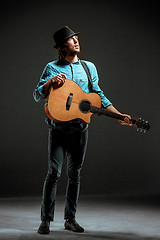 Image showing Cool guy standing with guitar on dark background