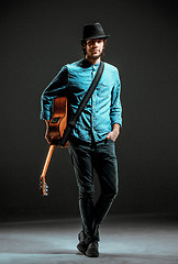 Image showing Cool guy standing with guitar on dark background