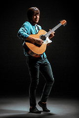 Image showing Cool guy standing with guitar on dark background