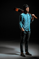 Image showing Cool guy standing with guitar on dark background