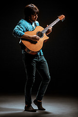 Image showing Cool guy standing with guitar on dark background