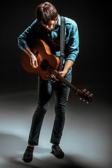 Image showing Cool guy standing with guitar on dark background