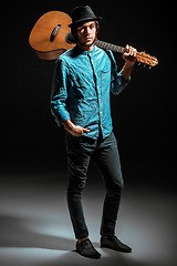 Image showing Cool guy standing with guitar on dark background