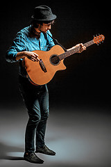 Image showing Cool guy standing with guitar on dark background