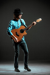 Image showing Cool guy standing with guitar on dark background