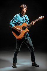 Image showing Cool guy standing with guitar on dark background