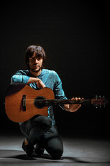 Image showing Cool guy standing with guitar on dark background