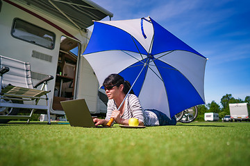 Image showing Woman on the grass, looking at the laptop under umbrella near th