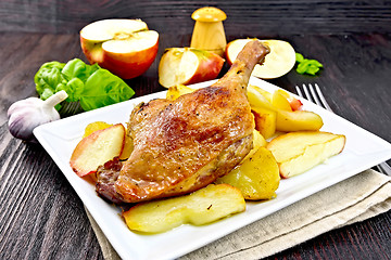 Image showing Duck leg with apple and potatoes in plate on napkin