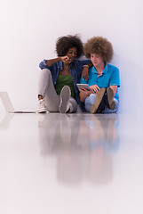 Image showing multiethnic couple sitting on the floor with a laptop and tablet