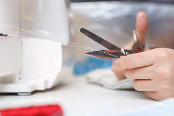 Image showing Girl with scissors cuts thread