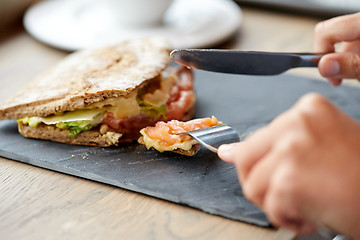 Image showing person eating salmon panini sandwich at restaurant