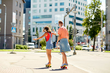 Image showing teenage couple riding skateboards on city street