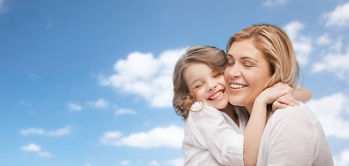 Image showing happy mother and daughter hugging over blue sky