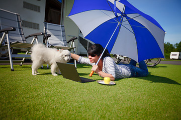 Image showing Woman on the grass with a dog looking at a laptop