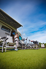 Image showing Woman is standing with a mug of coffee near the camper.