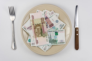 Image showing On the plate is a lot of money Russian rubles, lie next to utensils top view