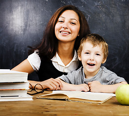 Image showing little cute boy with teacher in classroom at desk