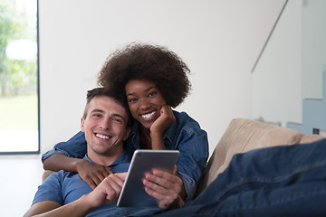 Image showing multiethnic couple relaxing at  home with tablet computers