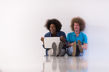 Image showing multiethnic couple sitting on the floor with a laptop and tablet