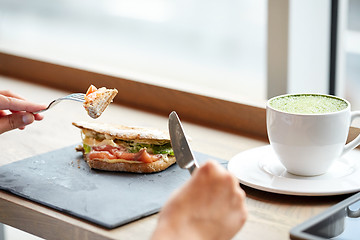 Image showing woman eating salmon panini sandwich at restaurant