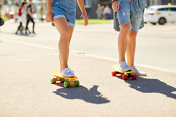 Image showing teenage couple riding skateboards on city street