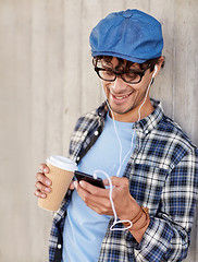 Image showing man with earphones and smartphone drinking coffee