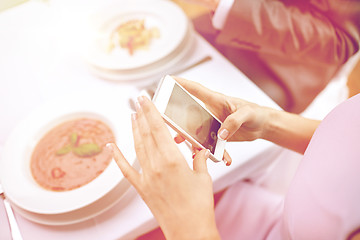 Image showing close up of couple with smartphones at restaurant