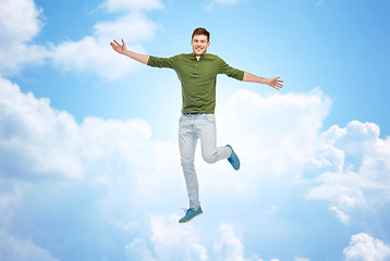 Image showing smiling young man jumping in air