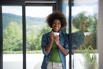 Image showing African American woman drinking coffee looking out the window