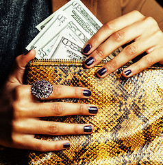 Image showing pretty fingers of african american woman holding money close up with purse, luxury jewellery on python clutch, cash for gifts