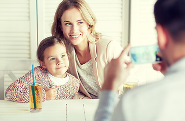 Image showing happy family picturing by smartphone at restaurant