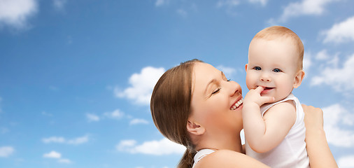 Image showing happy mother holding adorable baby over blue sky