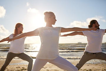 Image showing group of people making yoga exercises on beach