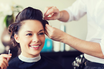 Image showing happy woman with stylist making hairdo at salon