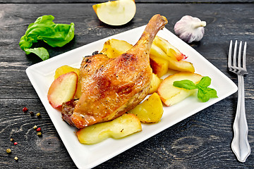 Image showing Duck leg with apple and basil in plate on board