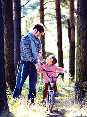 Image showing father learning his son to ride on bicycle outside in park