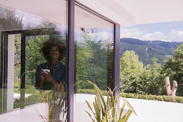 Image showing African American woman drinking coffee looking out the window