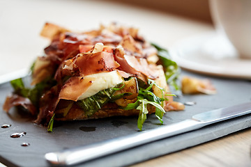 Image showing prosciutto ham salad on stone plate at restaurant