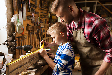 Image showing father and son with ruler measure wood at workshop