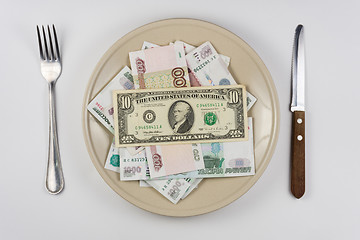 Image showing On the plate is a lot of money Russian rubles, they have a ten dollars banknote, lie next to utensils top view