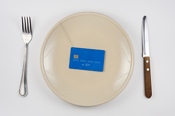 Image showing On the cracked plate is a plastic credit card, next lie fork and knife, white background, top view