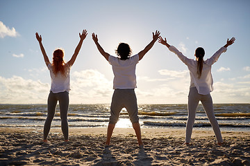 Image showing group of people making yoga or meditating on beach