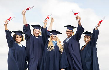 Image showing happy students in mortar boards waving diplomas